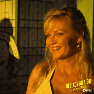 A Woman Is Smiling In Front Of A Sign That Says On Becoming A God In Central Florida GIF