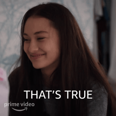 A Woman Is Smiling In Front Of A Sign That Says That 'S True On It GIF