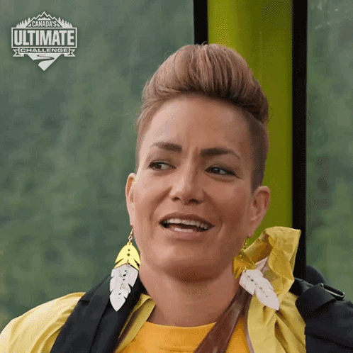 A Woman Is Smiling In Front Of A Sign That Says Ultimate Challenge GIF