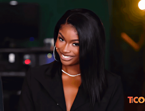 A Woman Is Smiling In Front Of A Tco Sign GIF