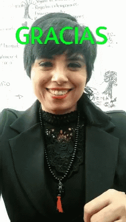 A Woman Is Smiling In Front Of A White Board That Says Gracias On It GIF