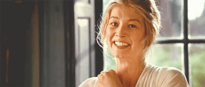 A Woman Is Smiling In Front Of A Window While Holding Her Arm Over Her Shoulder . GIF