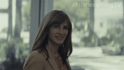 A Woman Is Smiling In Front Of A Window With #Homecomingtv Written On The Bottom GIF