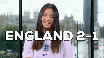 A Woman Is Smiling In Front Of A Window With The Words England 2-1 On It GIF