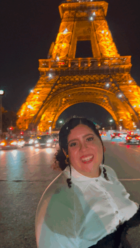 A Woman Is Smiling In Front Of The Eiffel Tower GIF