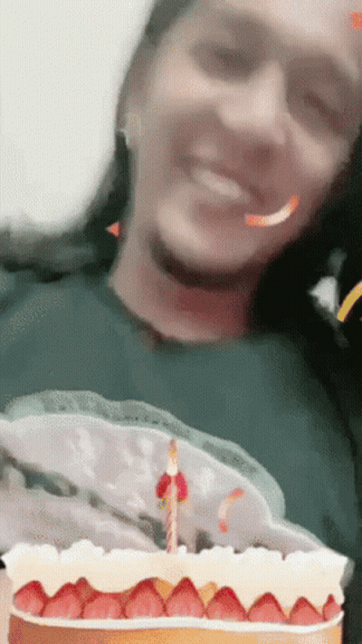 A Woman Is Smiling While Holding A Cake With Strawberries On It GIF