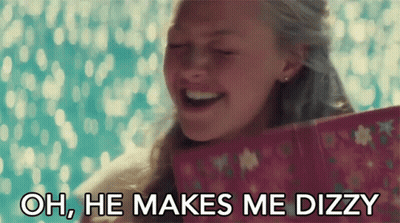 A Woman Is Smiling While Holding A Pink Gift Box And Says Oh He Makes Me Dizzy GIF
