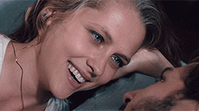 A Woman Is Smiling While Laying On A Man 'S Chest GIF
