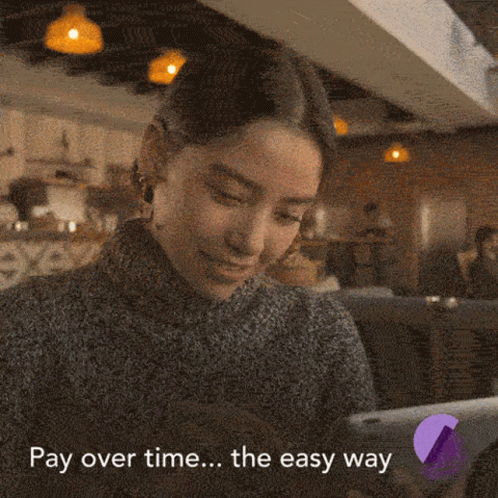 A Woman Is Smiling While Looking At A Tablet With The Words Pay Over Time The Easy Way Written Below Her GIF