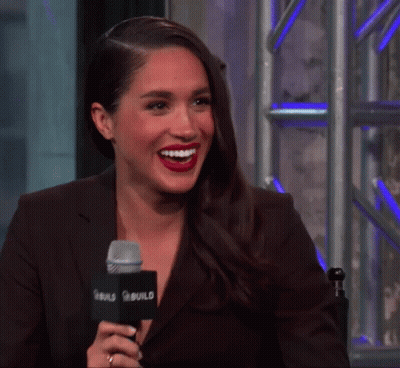 A Woman Is Smiling While Talking Into A Microphone That Says Build On It GIF