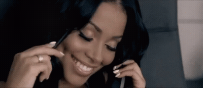A Woman Is Smiling While Talking On A Cell Phone And Wearing A Ring . GIF
