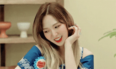 A Woman Is Smiling With Her Hand On Her Face While Wearing A Blue Shirt . GIF