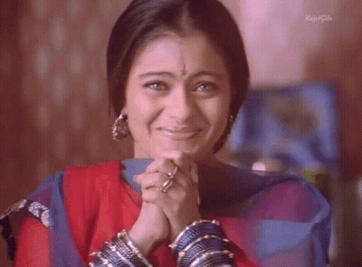 A Woman Is Smiling With Her Hands Folded In Front Of Her Face And The Words Kajal Girls On The Bottom GIF