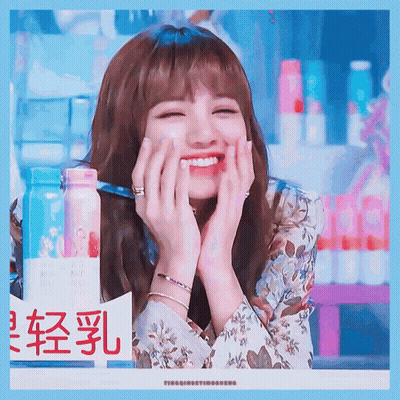 A Woman Is Smiling With Her Hands On Her Face In Front Of A Sign With Chinese Characters GIF