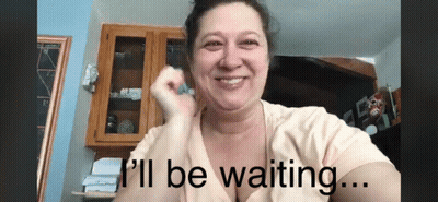 A Woman Is Smiling With The Words " I 'Ll Be Waiting " Below Her GIF