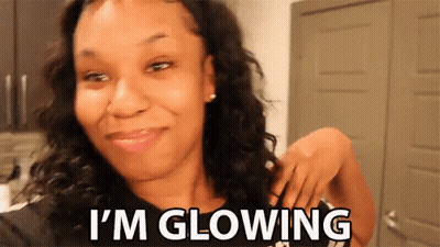 A Woman Is Smiling With The Words I 'M Glowing Below Her GIF
