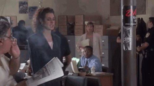 A Woman Is Smoking A Cigarette While Holding A Newspaper In Front Of A Group Of People . GIF