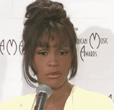 A Woman Is Speaking Into A Microphone In Front Of A Wall That Says American Music Award 'S GIF
