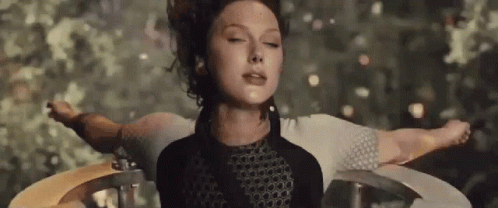 A Woman Is Standing In A Circle With Her Arms Outstretched And Her Eyes Closed . GIF