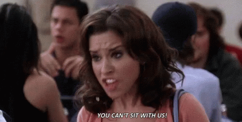 A Woman Is Standing In A Crowd Of People And Saying `` You Can 'T Sit With Us '' . GIF