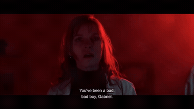 A Woman Is Standing In A Dark Room And Talking To A Boy . GIF