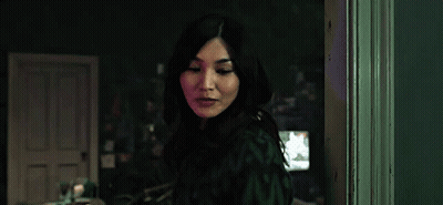 A Woman Is Standing In A Dark Room In Front Of A Door . GIF