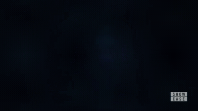 A Woman Is Standing In A Dark Room With Her Eyes Closed And A Show Case Logo In The Corner . GIF