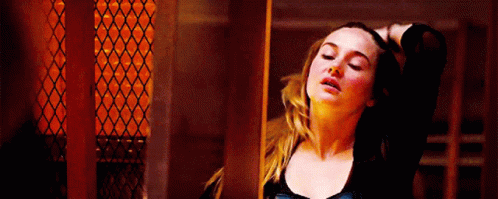 A Woman Is Standing In A Dark Room With Her Hand On Her Head . GIF