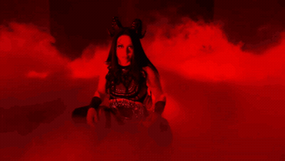 A Woman Is Standing In A Dark Room With Red Smoke Coming Out Of It GIF