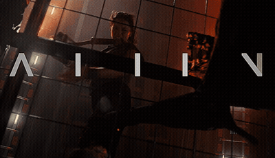 A Woman Is Standing In A Dark Room With The Letters N And I On The Bottom GIF