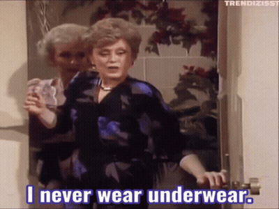 A Woman Is Standing In A Doorway Holding A Glass And Saying " I Never Wear Underwear " GIF