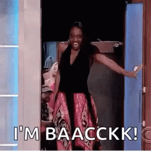 A Woman Is Standing In A Doorway With Her Arms Outstretched And Says `` I 'M Baacckkk '' . GIF