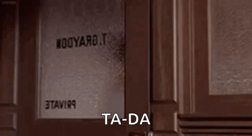 A Woman Is Standing In A Doorway With The Words `` Ta-Da '' Written On The Screen . GIF