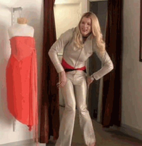A Woman Is Standing In A Dressing Room In Front Of A Mannequin Wearing A Red Dress . GIF