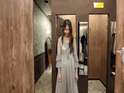 A Woman Is Standing In A Dressing Room With A Sign That Says Exit GIF
