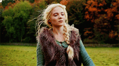 A Woman Is Standing In A Field Wearing A Fur Vest . GIF