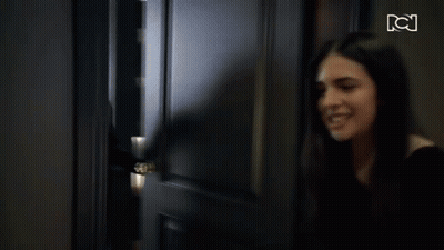 A Woman Is Standing In A Hallway With A Tv Screen Behind Her That Says Tci GIF