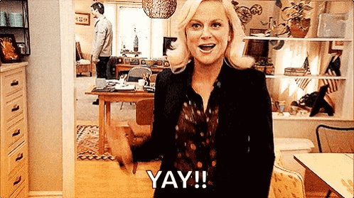 A Woman Is Standing In A Living Room And Saying Yay ! GIF