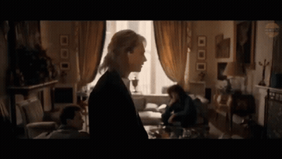 A Woman Is Standing In A Living Room Next To A Man And A Woman . GIF