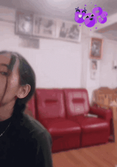 A Woman Is Standing In A Living Room With A Red Couch And A Purple Butterfly On The Wall . GIF
