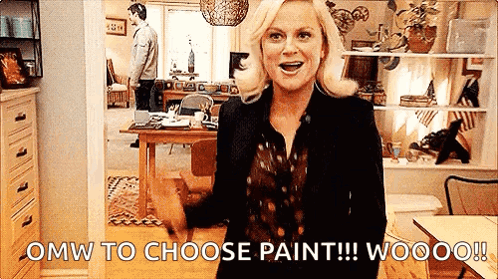 A Woman Is Standing In A Living Room With The Words `` Omw To Choose Paint !!! Wooo ! '' GIF