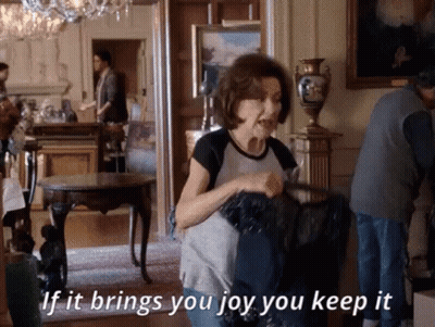 A Woman Is Standing In A Room Holding A Black Bag And Says If It Brings You Joy You Keep It . GIF