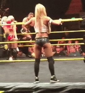 A Woman Is Standing In A Wrestling Ring With A Crowd In The Background GIF