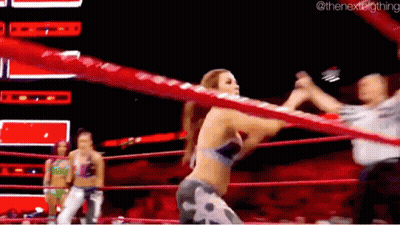 A Woman Is Standing In A Wrestling Ring With A Referee . GIF