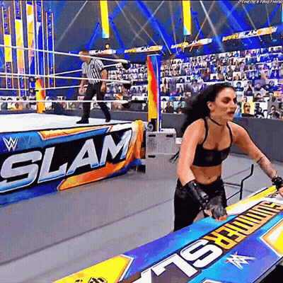 A Woman Is Standing In A Wrestling Ring With A Sign That Says Slam . GIF