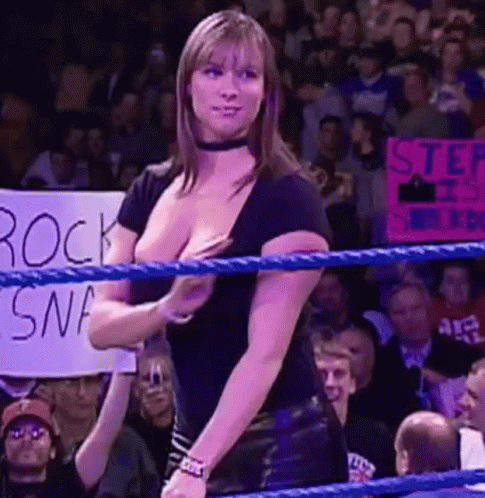 A Woman Is Standing In A Wrestling Ring With A Sign That Says `` Step It Up '' . GIF