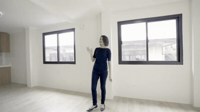 A Woman Is Standing In An Empty Room With A Lot Of Windows GIF