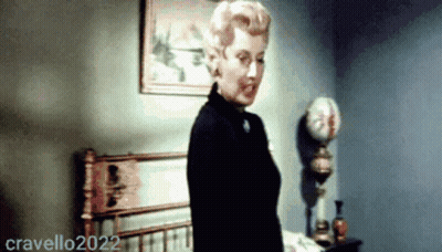 A Woman Is Standing In Front Of A Bed In A Room With The Year 2022 On The Bottom Right GIF