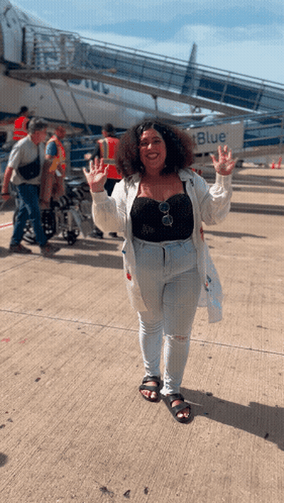 A Woman Is Standing In Front Of A Blue Airplane GIF