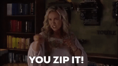 A Woman Is Standing In Front Of A Bookshelf With A Fist In The Air And Saying `` You Zip It ! '' GIF